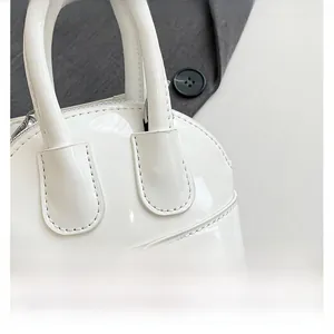 Détail du mini sac bandoulière en cuir verni blanc avec finition brillante et poignée