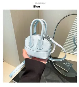 Détail du sac coquille en cuir verni bleu clair avec poignées et bandoulière