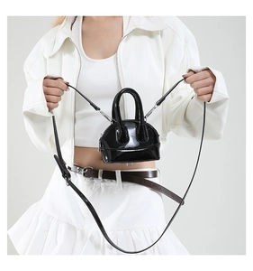 Détail d'un mini sac bandoulière en cuir verni noir avec des finitions argentées