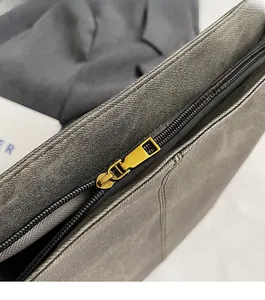 Detailed macro view of smooth gold zipper and pebble grain texture on grey tote bag
