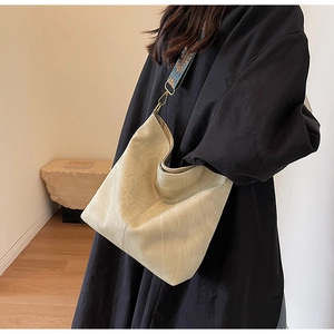 Detail of minimalist cream tote bag featuring bohemian embroidered wide strap on model