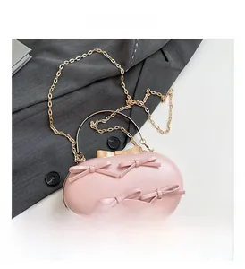 Close-up of pink evening clutch with bow details, gold handles, and detachable chain strap