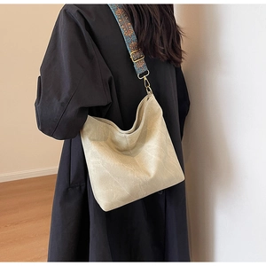 Detail of hobo tote bag featuring a beige suede finish and ethnic embroidered wide strap