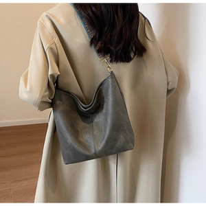 Detail view of grey tote bag with ethnic geometric wide shoulder strap on a model