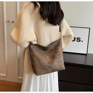 Détail du sac fourre-tout marron foncé avec cuir texturé et bandoulière large à motifs