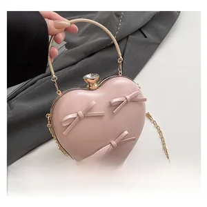 Detail of pink heart-shaped clutch with handmade bows and golden metal ring handle