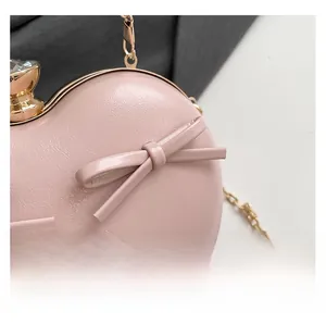 Detailed close-up of pink heart-shaped evening bag with litchi texture and crystal clasp