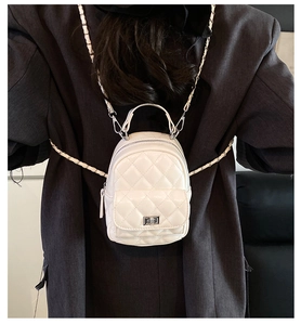 Detailed back view of model wearing a white quilted mini backpack with gold chain straps