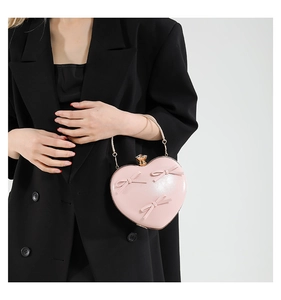 Detail of pink heart-shaped evening bag with bow accents and gold metal handle