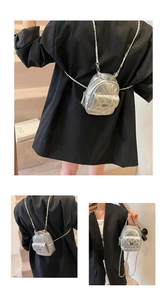 Close-up of quilted silver mini backpack with metal chain strap and twist-lock detail