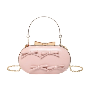 Pink oval evening clutch bag with bow detailing and golden chain strap in 45-degree view