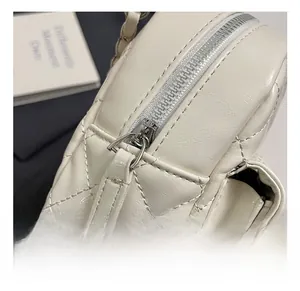 Close-up of premium quilted cream faux leather bag with high-quality silver metal zipper