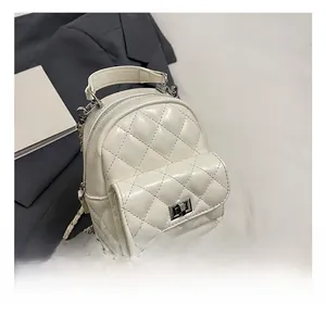 Detail of white quilted backpack with metal turn-lock and leather chain straps