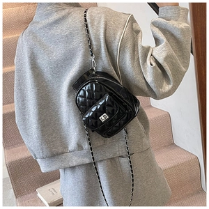 Close-up of quilted black patent leather mini backpack with silver twist lock and chain strap