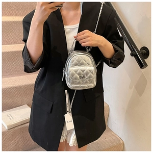 Detail of silver quilted mini backpack with chain strap and twist lock on stairs