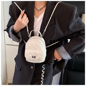 Detail of white quilted mini backpack with silver metal turn lock and chain strap