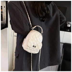 Detail of off-white quilted mini backpack with metal chain strap and twist lock