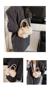 Detail view of woven texture beige Boston bag set with a matching mini pouch and strap