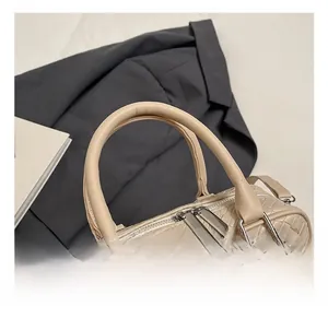 Detail of comfort handles and woven texture on a beige luxury shoulder bag for women