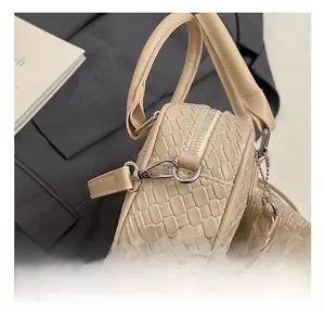 Close-up of beige crocodile pattern handbag with durable silver metal hook and strap details