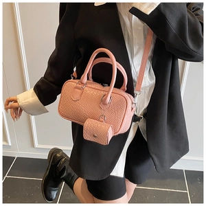 Pink Boston bag with crocodile texture and mini pendant on a professional model