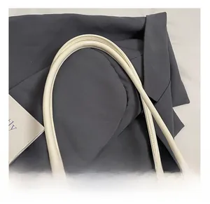 Gros plan sur la poignée en similicuir crème avec coutures premium sur un sac à main