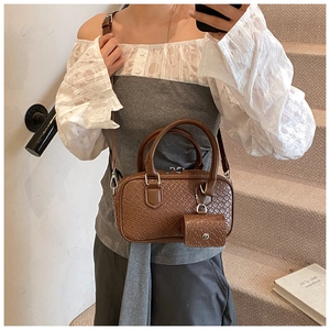 Detailed close-up of brown crocodile texture leather boston bag with a small coin purse