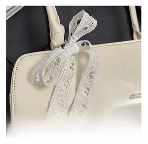 Détail du sac à main crème rectangulaire avec texture cuir lisse et ruban en dentelle