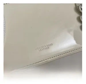 Gros plan du cuir verni crème avec lettrage embossé et coutures de précision