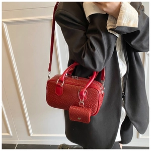 Detail of red woven Boston bag with small charm pouch and elegant leather texture