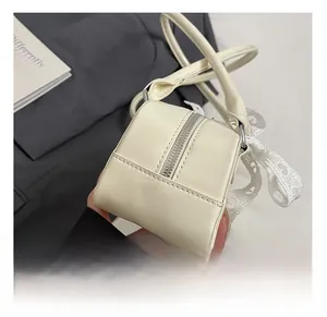 Détail du sac en similicuir blanc crème avec ruban en dentelle et zip argenté