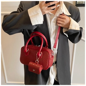 Detail of red woven shoulder bag with mini pouch on a model in a black suit