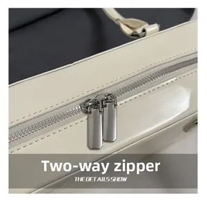 Gros plan d'un sac en cuir verni blanc brillant avec détail de fermeture éclair argentée
