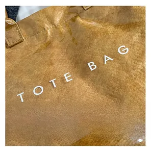 Dettaglio della borsa tote in Tyvek marrone con scritta bianca e cuciture della maniglia