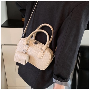 Detail of cream woven leather bowling bag showing mini pouch and silver hardware on model