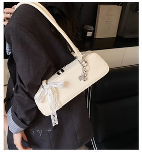 Détail du sac sous l'épaule blanc crème avec nœud en dentelle et pendentif cœur