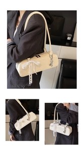 Elegant off-white patent leather baguette shoulder bag with lace bow and charm detail.