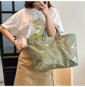 Dettaglio borsa tote verde in carta Tyvek con texture stropicciata e scritta TOTE BAG bianca