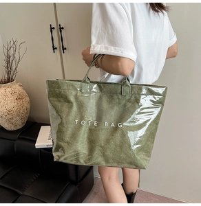 Dettaglio della borsa tote in carta Dupont verde oliva con strato in PVC e scritta TOTE BAG
