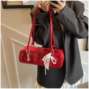 Red patent leather baguette shoulder bag detail with cute white lace bow and metal heart charm.
