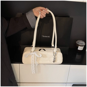 Détail du sac à bandoulière en cuir PU blanc crème avec nœud en dentelle et pendentif