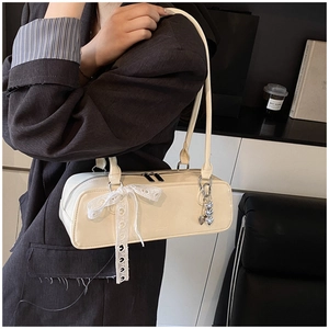 Chic patent leather cylindrical shoulder bag with elegant lace bow and silver heart charm.