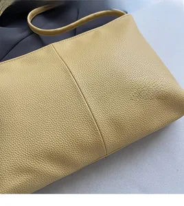 Detail of yellow lychee grain leather tote bag with soft texture and vertical stitching
