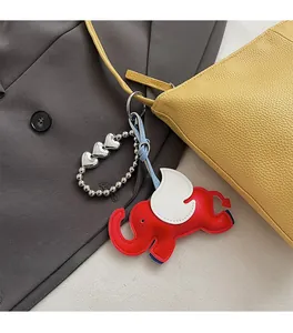 Close-up of a creative red elephant leather bag charm with white wings and silver chain
