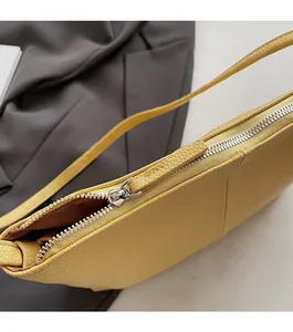 Detailed close-up of smooth silver metal zipper and lychee pattern on yellow hobo bag
