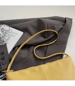 Detail of yellow lychee grain leather shoulder bag with sleek strap and zipper closure