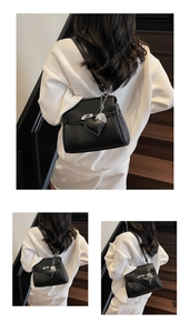 Detailed close-up of black litchi pattern leather bag with silver heart charm and lock