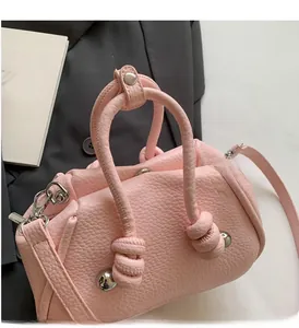 Borsa a mano rosa testurizzata con manici a nodo e dettagli con borchie argentate su abito