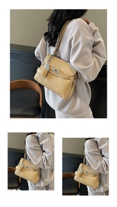 Detailed macro view of litchi textured beige handbag with heart pendant and metal turn lock