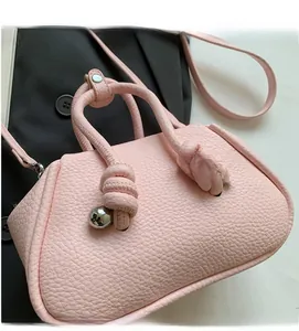 Dettaglio borsa rosa a grana litchi con sfera d'argento e design del manico a nodo